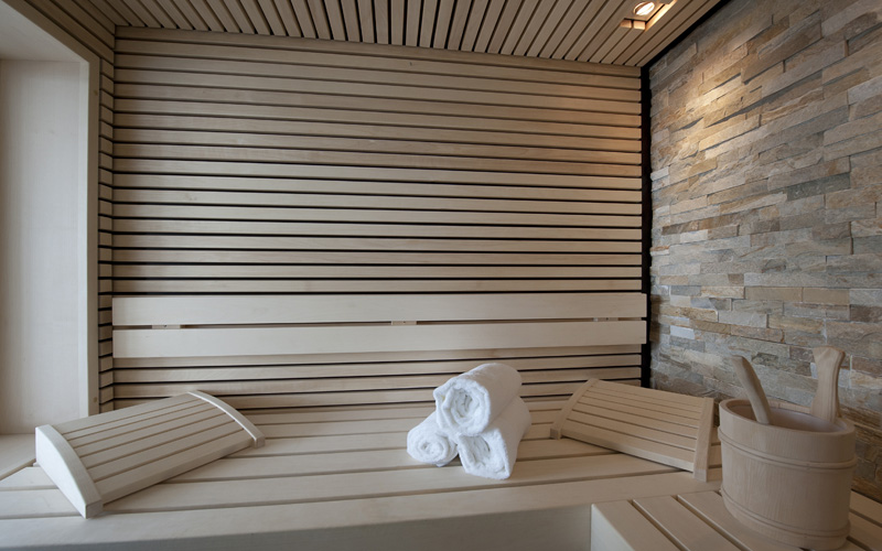 schöne Sauna mit Steinwand und Deckenspots sowie integriertem Fenster