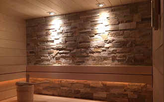 schone-sauna-mit-steinwand-deckenspots-beleuchtung-in-rückenlehne-breites-täfer-espe-025a